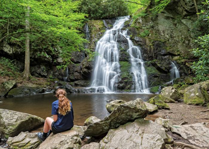 A person rests by a waterfall during their hike in the smoky mountains