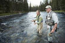 A man and woman fly fish in a river on a clear day