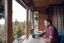 man working on laptop from mountain cabin