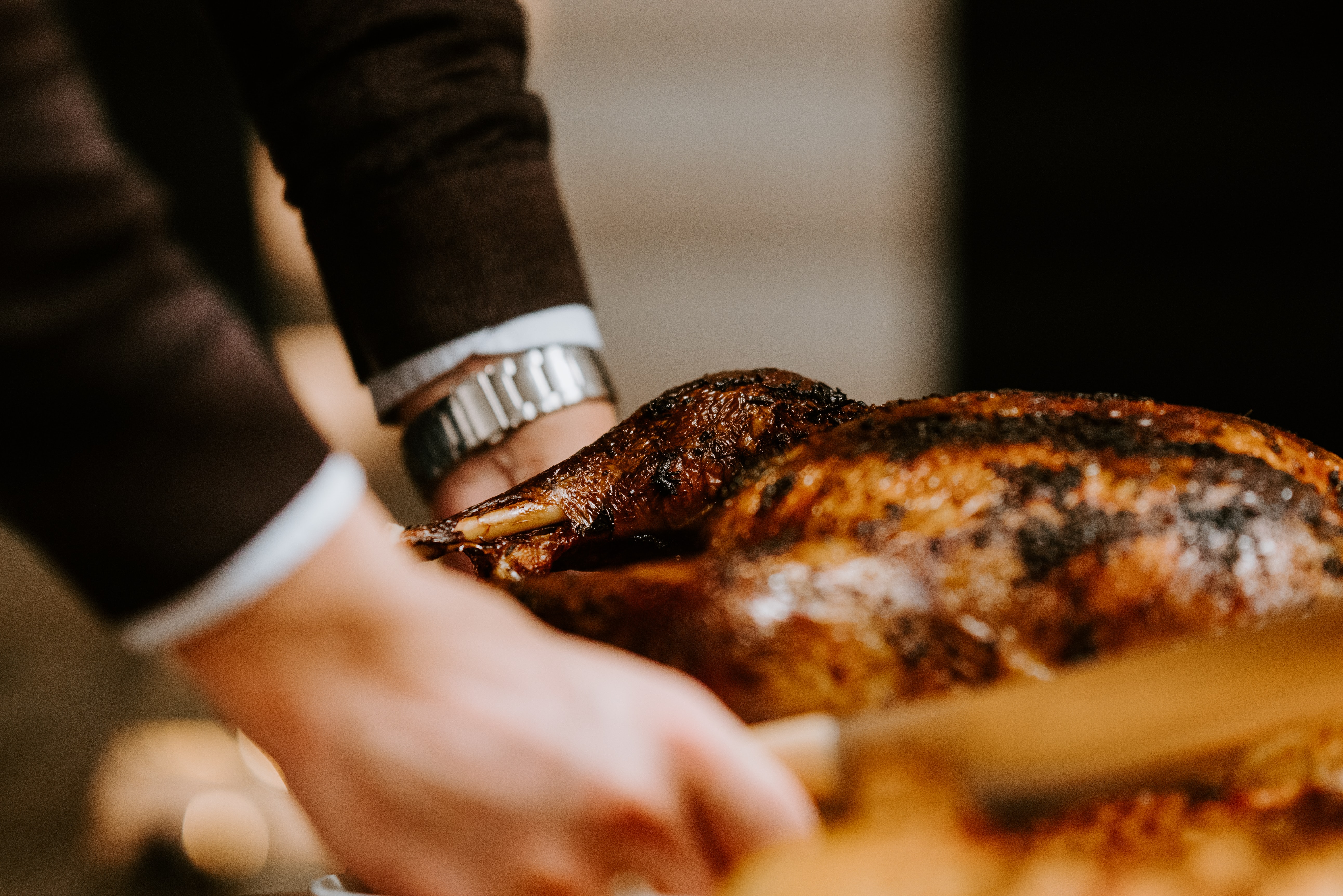 A pair of hands puts down a roasted turkey